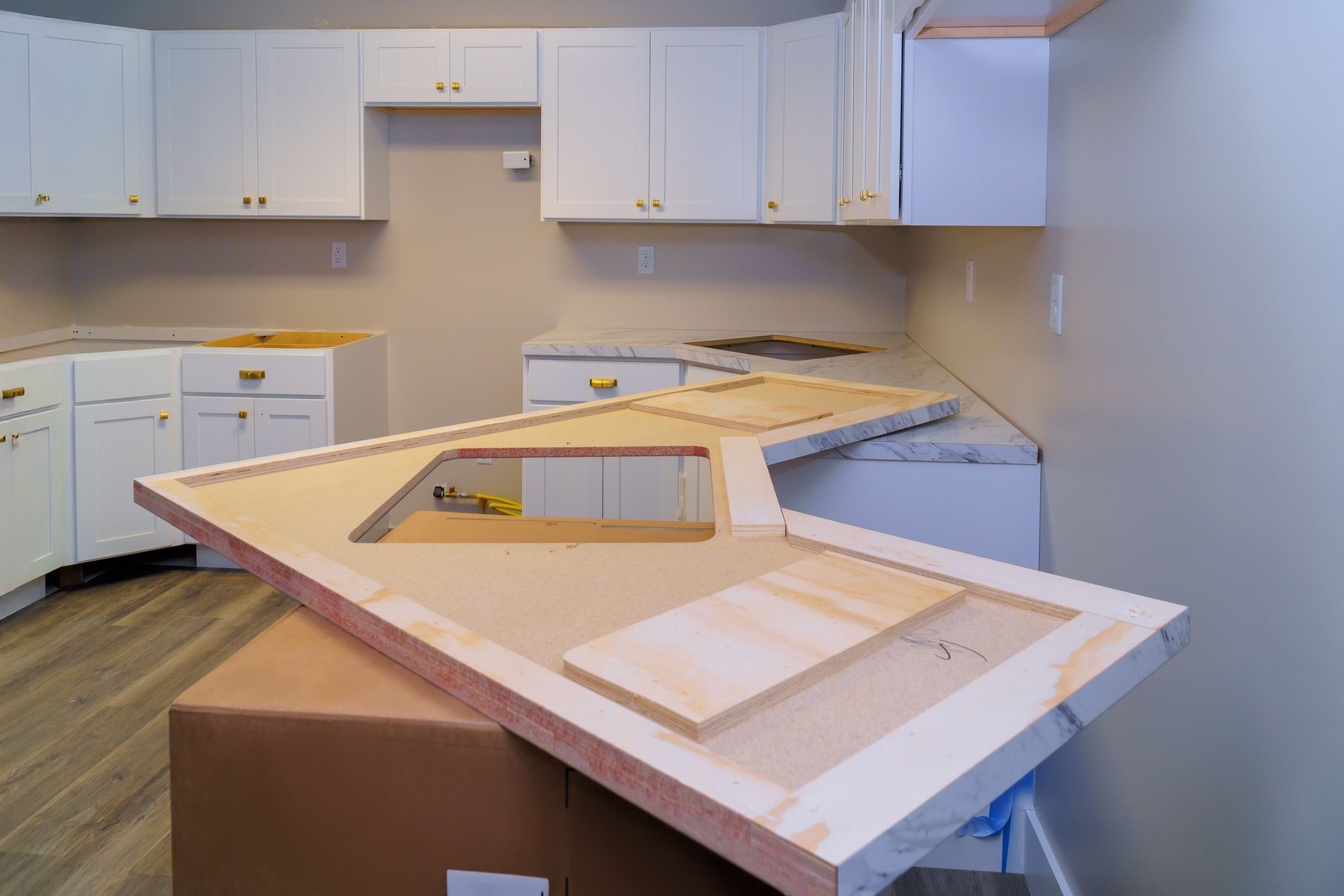 New kitchen layout featuring white cabinets marble countertop being installed in modern home renovation project